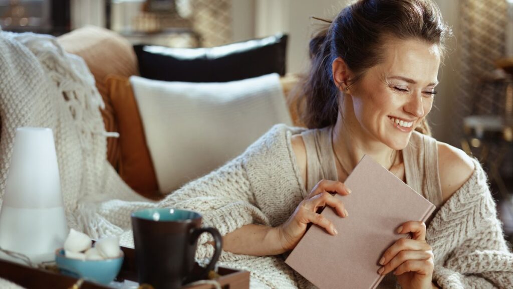 Woman holding book in a cozy, Hygge room