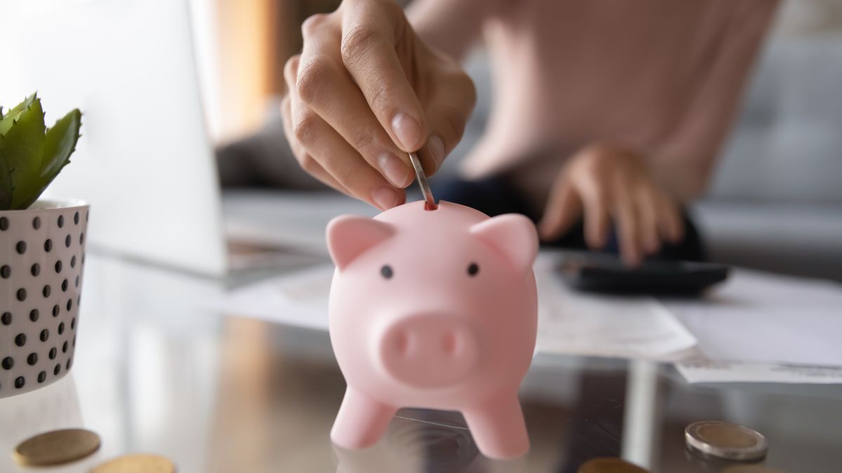 Woman putting change into a pink piggy bank