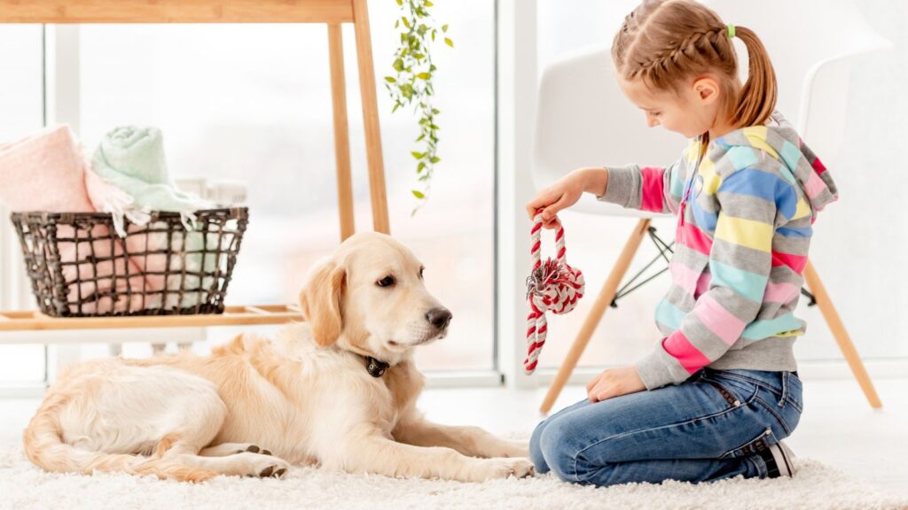 Young girl sitting on the floor playing with her dog