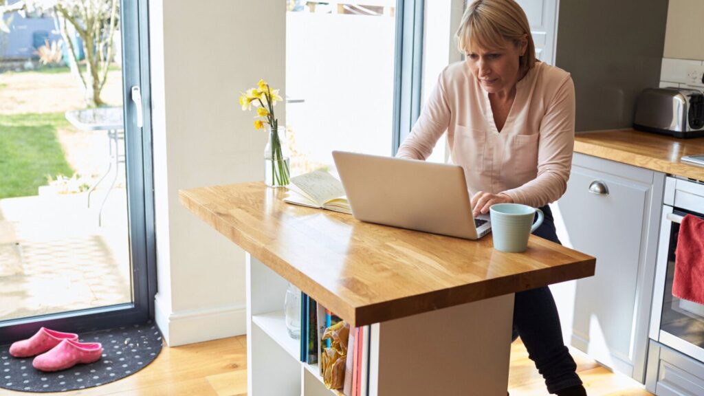 Woman sitting at her kitchen island working on her laptop