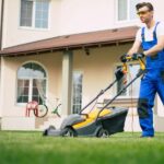 Man in overalls mowing lawn with push mower
