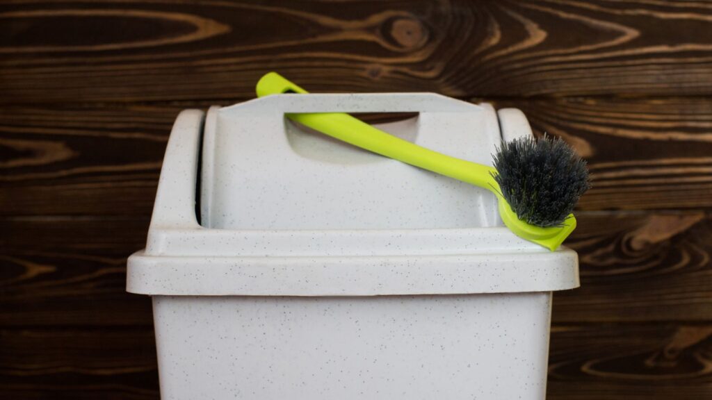 Trash can with a brush stuck in the lid