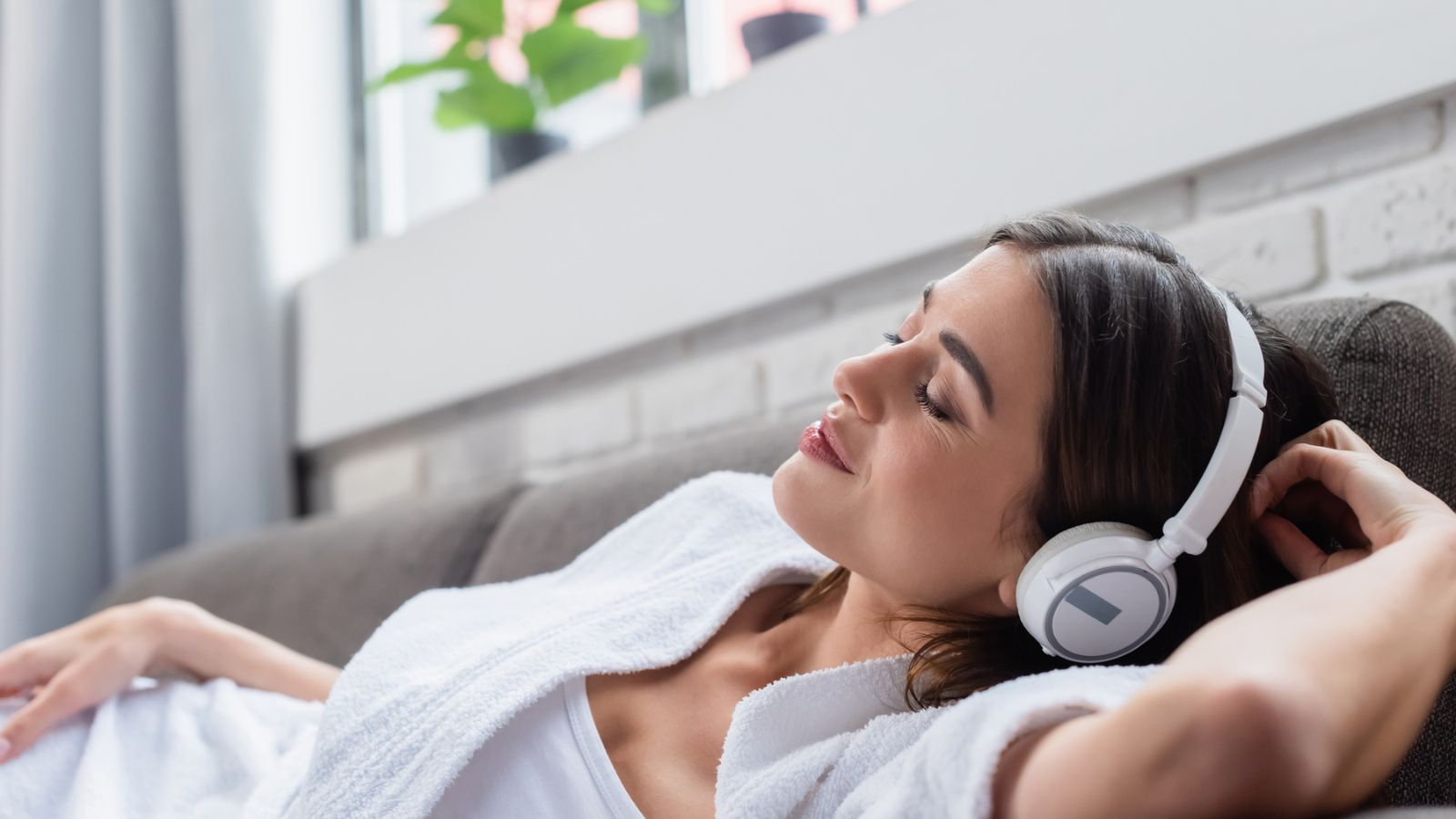 Young woman relaxing on the couch wearing headphones