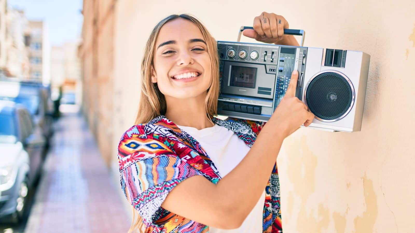 Teenage girl smiling and carrying a boombox on her shoulder