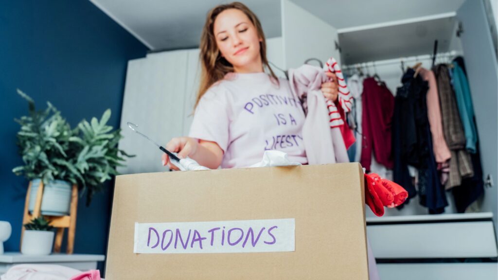 Woman cleaning out her clothes and putting them in a box to donate
