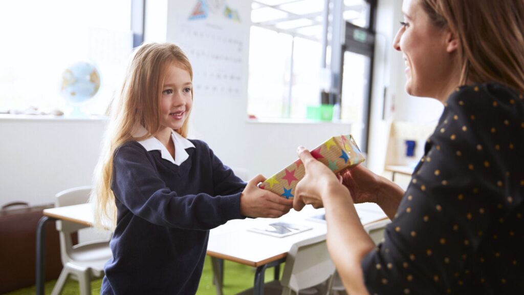 Young girl handing her teacher a gift
