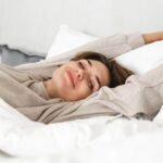 Woman waking up happily and stretching in bed