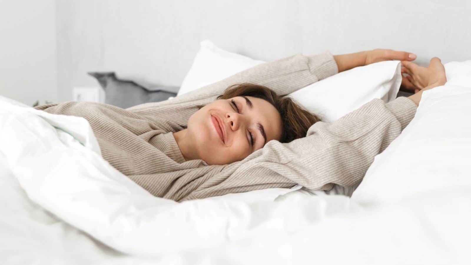 Woman waking up happily and stretching in bed
