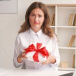 Woman holding a gift looking completely unimpressed