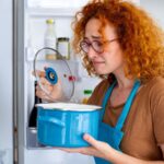 Redhead woman smelling a pot in the refrigerator