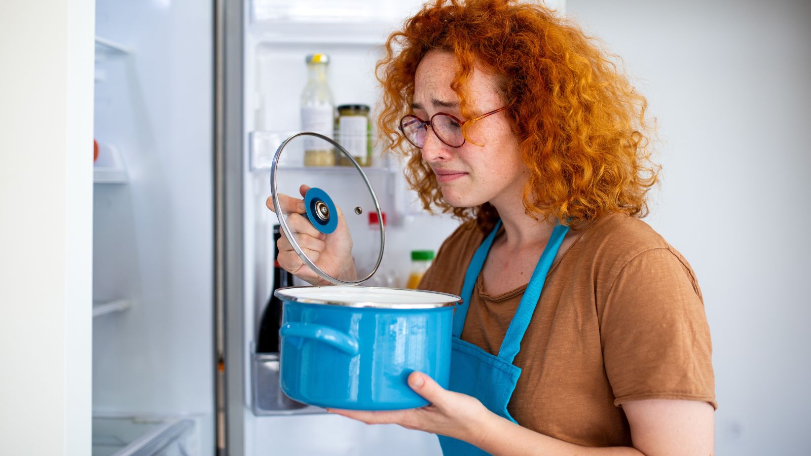 Redhead woman smelling a pot in the refrigerator