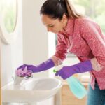 Woman wearing gloves and cleaning the bathroom