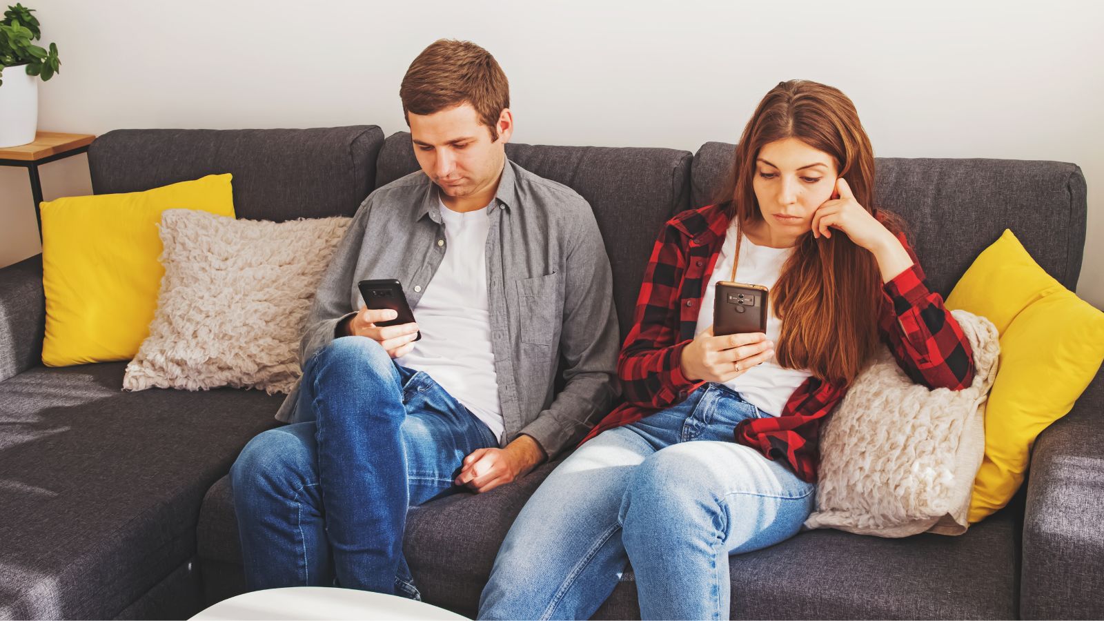 Couple sitting on the couch using their cell phones