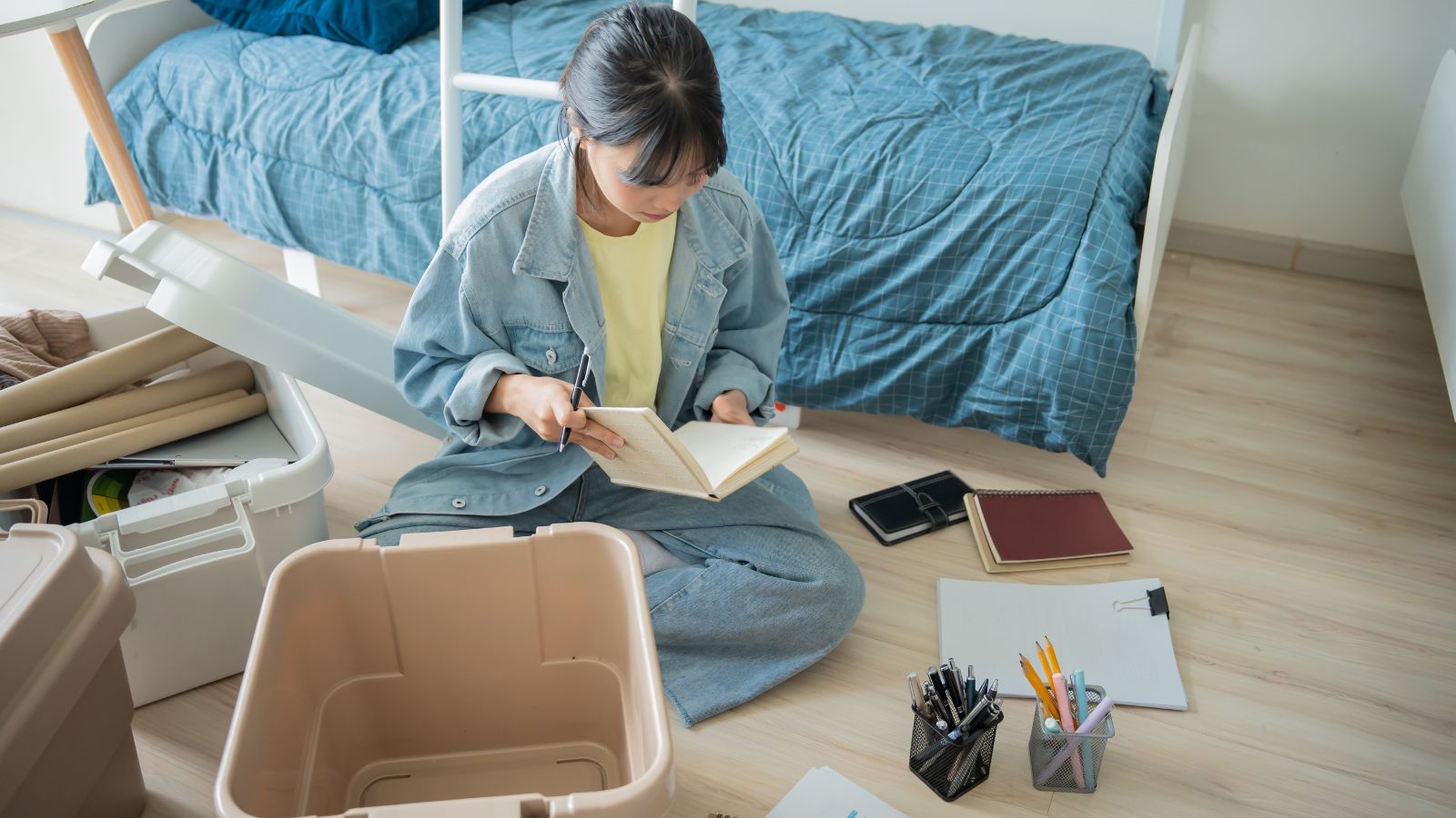 Young woman sitting on the floor organizing her room