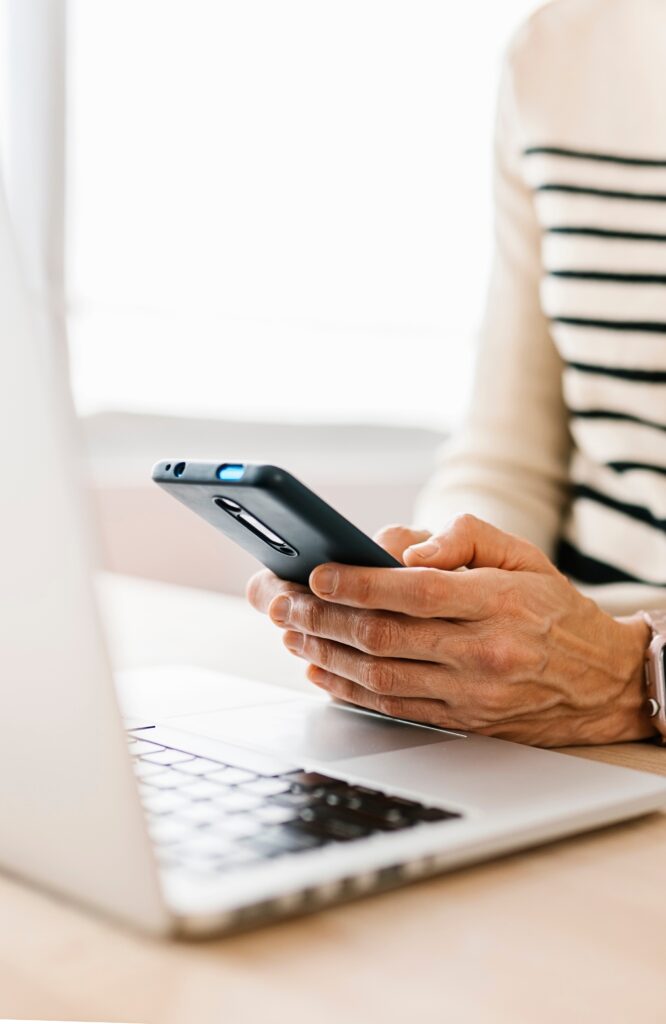 Woman using laptop and cell phone