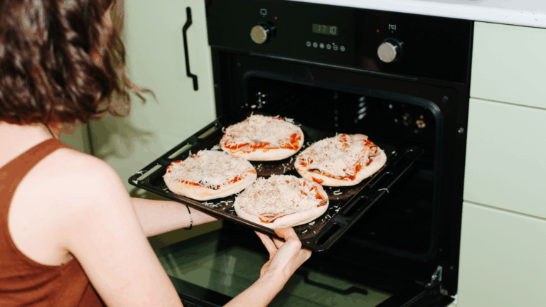 Woman putting small frozen pizzas in the oven