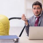 Exhausted dad sitting at desk with stroller next to him