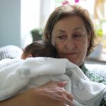Elderly woman holding a newborn baby