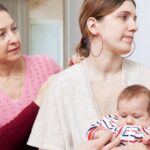 Mother-in-law sitting with her daughter-in-law and holding her baby