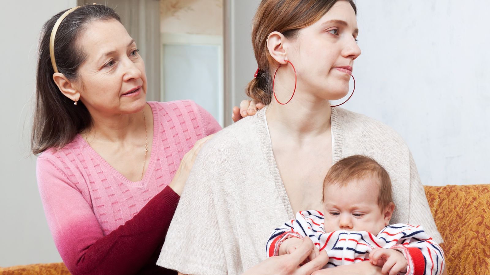 Mother-in-law sitting with her daughter-in-law and holding her baby