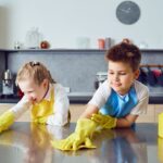 Kids wearing gloves and wiping the counter