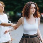 Young man grabbing young woman's arm as she's walking away