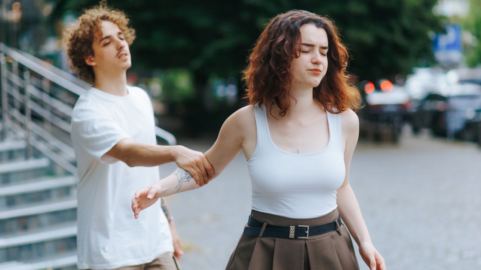 Young man grabbing young woman's arm as she's walking away