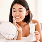 Young woman applying a skincare product to her face