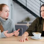 Female friends drinking coffee and arguing