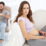Worried pregnant woman with man on his phone