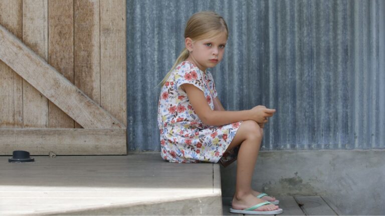 Young girl sitting alone on a step looking annoyed