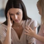 Young woman babysitting looks frustrated with the child