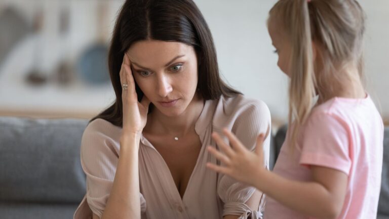 Young woman babysitting looks frustrated with the child