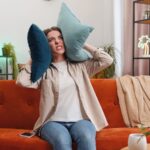 Woman looking angry and covering her face with pillows