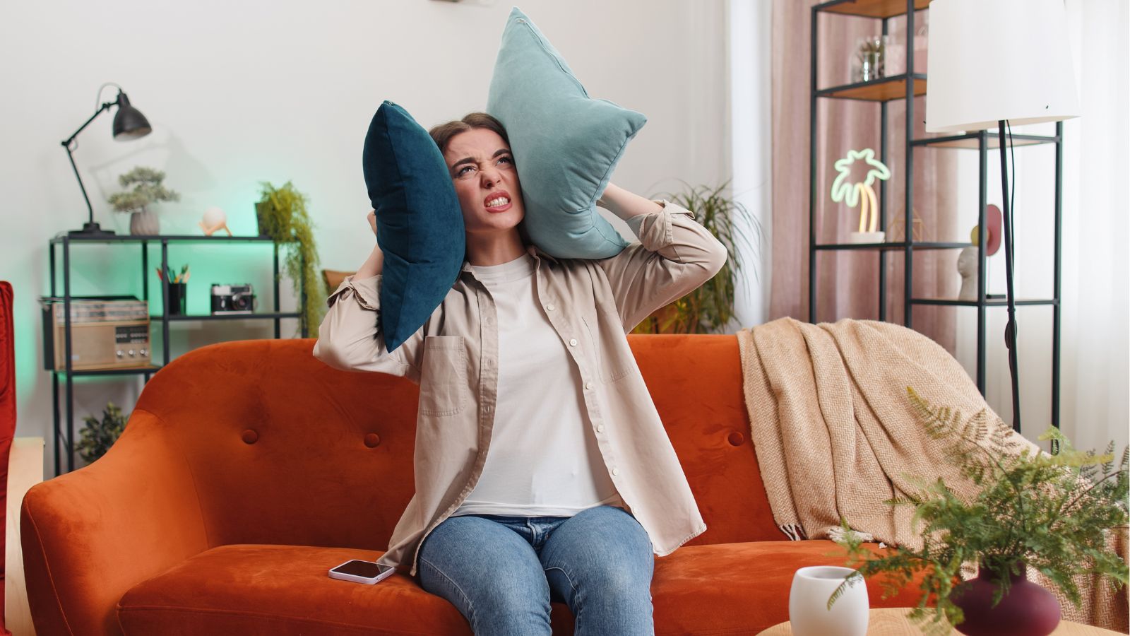 Woman looking angry and covering her face with pillows