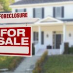 For sale forecosure sign in front yard of house