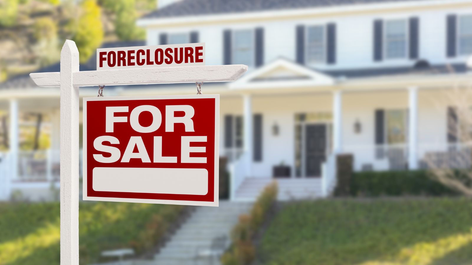 For sale forecosure sign in front yard of house