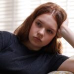 Teenage girl sitting on couch looking sad