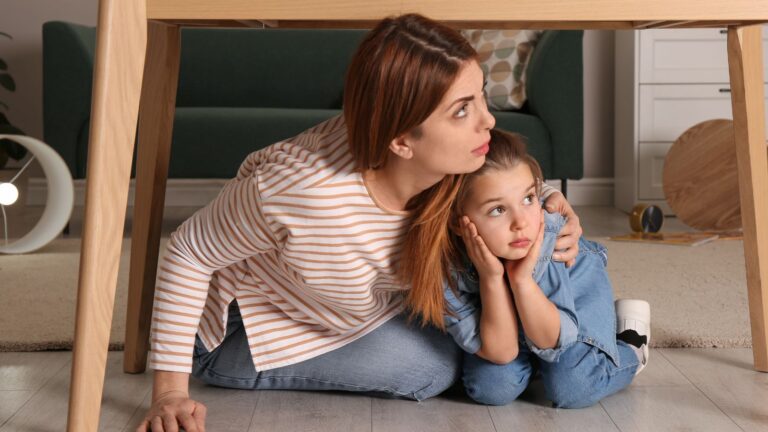 Woman and girl hiding scared under a table