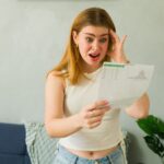 Woman looking shocked at a bill she is reading