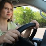 Young woman looking annoyed while driving