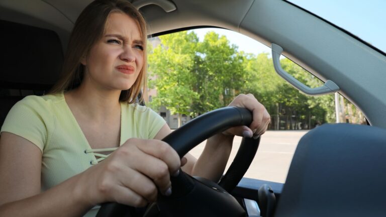 Young woman looking annoyed while driving