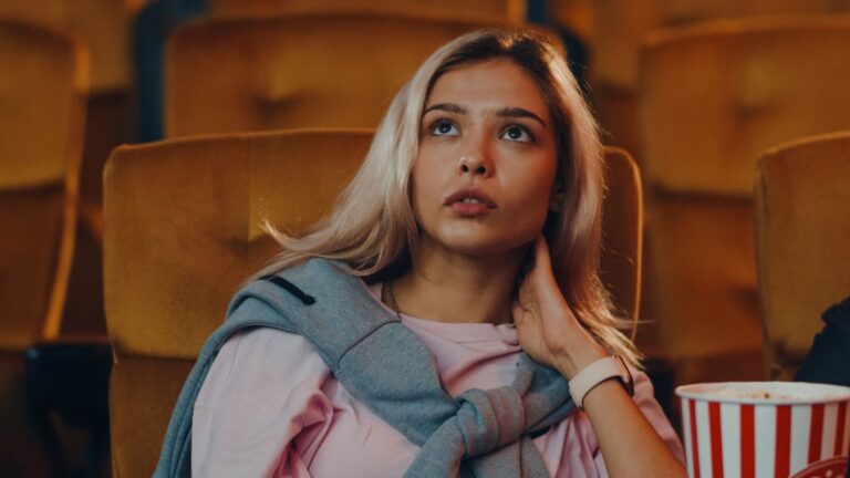 Young woman sitting alone in a theater with popcorn