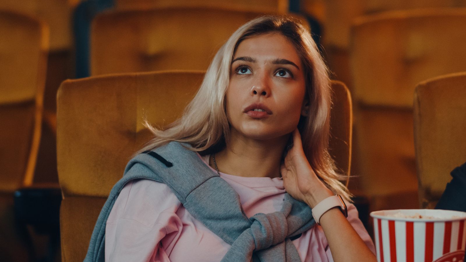 Young woman sitting alone in a theater with popcorn
