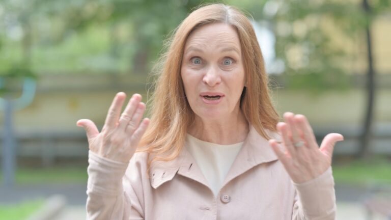 Middle-aged woman looking upset with her hands up