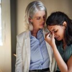 Older woman comforting younger woman upset at work