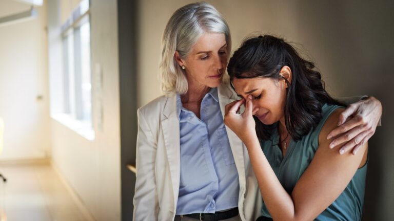 Older woman comforting younger woman upset at work
