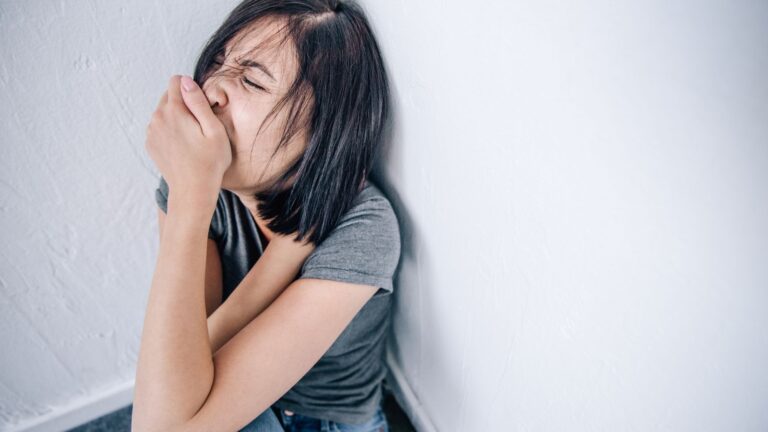 Teenage girl sitting on the ground crying