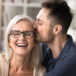 Adult son hugging his mother and kissing her cheek