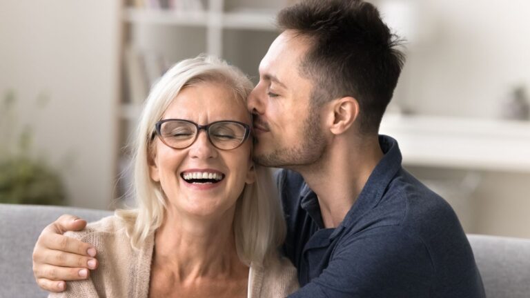 Adult son hugging his mother and kissing her cheek